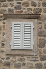 Traditional new white window shutters as blinds on old stone home