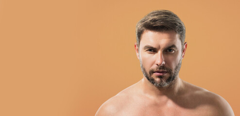 Close up beauty portrait of half naked satisfied young man after facial cream. Attractive brunet guy touching skin. Men model face with beard and modern haircut. Banner for header, copy space.