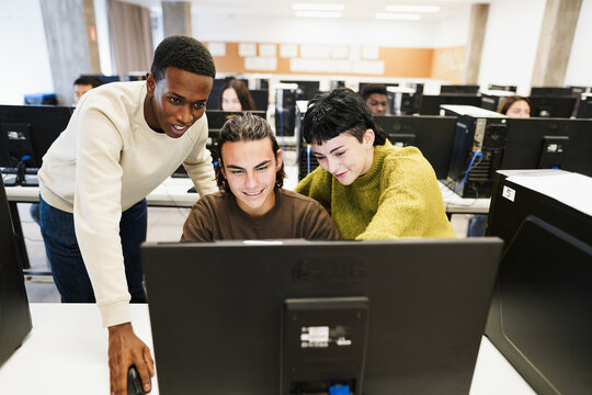 Multiracial students using personal computer at IT college class - Back to school and campus lifestyle concept - Main focus on center male face - Powered by Adobe
