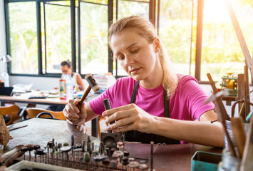 Young female jeweler making jewelry in workshop