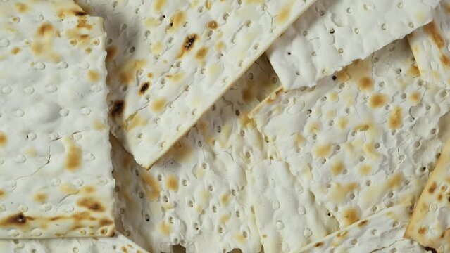 Matzah or Matzo kosher food for Passover, made from flour and water. Unleavened flatbread. Jewish cuisine. 4K Video, Rotating.