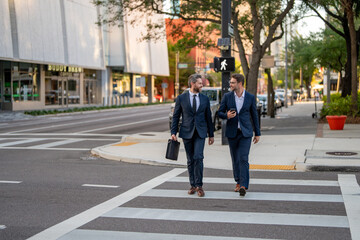 Planning of the two business mens strategy. Business men walking across the crosswalk on american city street outdoor.