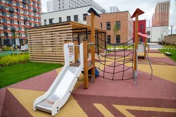 A wooden slide with a gazebo on the playground in kindergarten against the background of houses on a clear sunny day. Playgrounds, toys, sports.