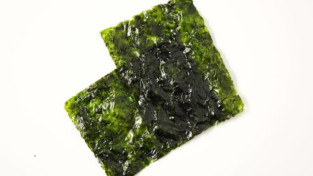 Gimgui or fried seaweed. Green Edible seaweed Undaria pinnatifida also called as wakame, sea mustard or nori. 4K Video, Rotating.