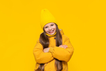 A young girl on an autumn day. A child in a beanie hat and a warm down jacket. A charming little...