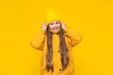 A young girl is warming herself in a warm autumn jacket. A little girl in a down jacket and a hat...
