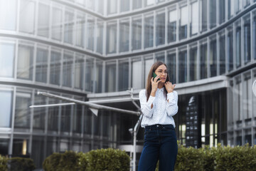 Portrait of a successful business woman talking using mobile phone in front of modern business building