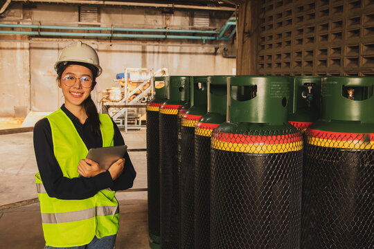 Portrait asian female safety engineer engineer inspector in industrial factory using digital tablet inspects safe ammonia chemical refrigerant tanks with well ventilated storage space for safety. - Powered by Adobe