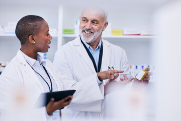 Conversation, tablet and pharmacists checking medication for inventory, stock or medical research. Healthcare, medicine and senior chemist mentor teaching female pharmaceutical student with tech.