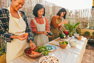 Asian family cooking together at home patio outdoor - Mother and two daughters having fun preparing...