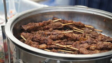 Grilled lamb satay on a serving tray.
