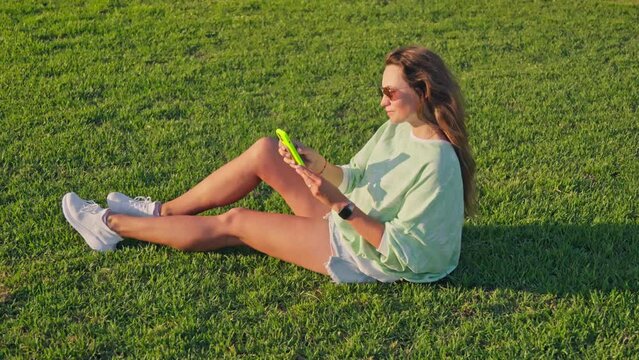 Girl takes selfie sitting on the grass
