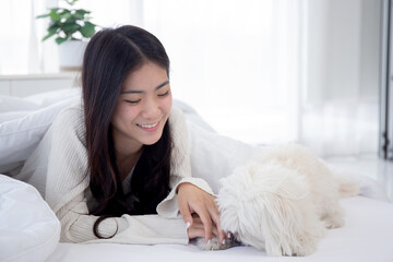 Beautiful young asian woman playful with fluffy dog shih tzu for relax with love on bed in bedroom at home, friends pet with companion, friendship of woman and animal, female and friendly of puppy.