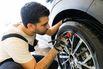 Mexican worker cleaning the car tires at auto detail service
