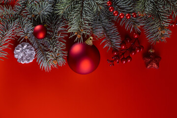 Fir branches and Christmas decorations on a red background. Copy space