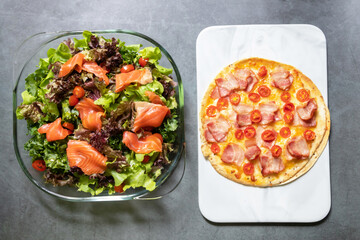 Delicious gourmet pizza smoke bacon, cheese and tomato with smoke salmon salad on black table background. Homemade delicious pizza. Top view and copy space.
