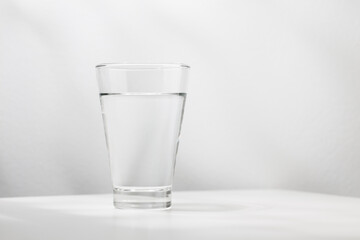 Pure water in the glass is on the white wooden table.