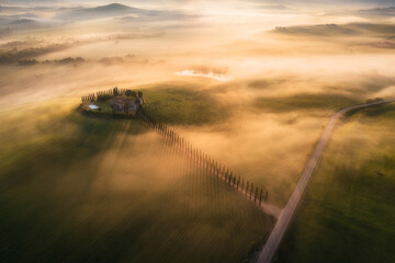 Aerial view of the goggy landscape at farmhouse Poggio Covili at sunrise in Val d'Orcia, Tuscany, Italy