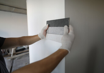 Male builder selects color for painting putty wall. Choose color for room. Plastering flat...
