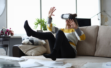 Close-up of young woman touch something using modern virtual reality glasses. Pretty female sitting...