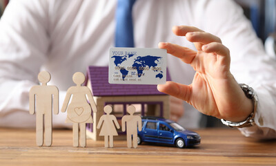 Figures family stand in background house and car. Credit purchase of a house and family car. Parents care about the well-being of their children. Profitable property loan. Man holds credit card