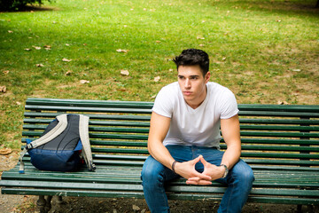 Obraz premium Photo of a man sitting on a bench with a backpack