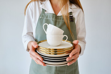 A woman holds a stack of clean plates in a cup. Crockery close-up