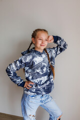 Little girl with blond long hair in two pigtails in new clothes for product demonstration sale in the store