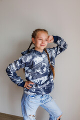 Little girl with blond long hair in two pigtails in new clothes for product demonstration sale in...