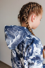 Little girl with blond long hair in two pigtails in new clothes for product demonstration sale in the store