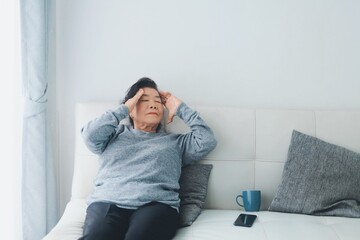 Fototapeta premium Asia senior woman lying on sofa feeling headache.