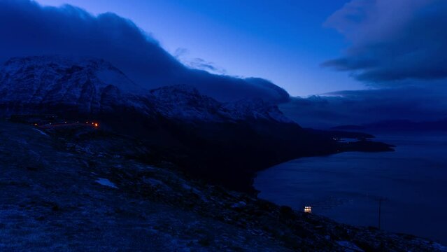 Timelapse of snowy blue colored evening mountains and a fjord in northern Norway