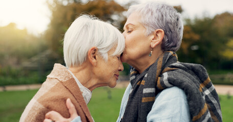 Senior woman kissing her friend on the forehead for affection, romance and bonding on outdoor date. Nature, commitment and elderly female couple in retirement with intimate moment in garden or park.
