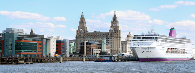 Panoramic skyline shot of Liverpool Pier Head waterfront with a big cruise ship by the iconic Royal Liver Building in the centre