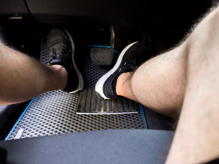 A man's feet put the pedals of the car controls