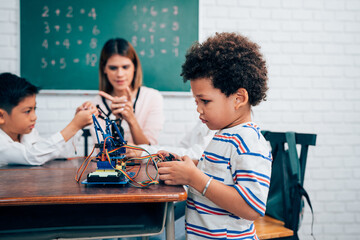 Happy school teacher and students having interesting engaging activities in class. Little children sitting around classroom table, talking and playing fun games together