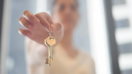 Real estate agent is holding a key in front of blurred background, concept of house sale, purchase, investment, mortgage, insurance and security - Powered by Adobe