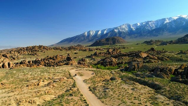 Aerial Shot Of Vehicle Moving On Dirt Road With Mountains In Background Against Sky, Drone Flying Forward Over Landscape - Alabama Hills, California