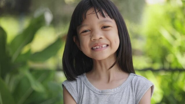 Close-up portrait of the bright face of Asian Thai kid girl aged 6 to 8 years, smiling beautifully, showing her growing teeth. She was a healthy and strong girl with beautiful long black hair.