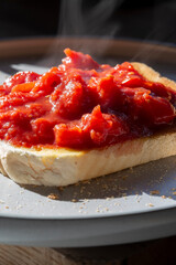 Chopped cherry tomatoes on a slice of white bread toast. On a grey plate