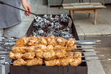 Tender and juicy chicken skewers are cooked on the coals in an open grill. Delicious kebab or barbecue