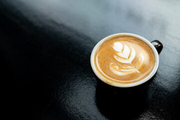 Coffee cup with latte art on black background