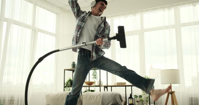 Man is shown tidying the living room while listening to music. With a content and relaxed expression, he enjoys the rhythm of the music while completing his cleaning tasks.