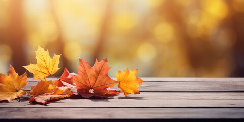 Naklejka na ściany i meble Autumn maple leaves on wooden table with bokeh background.
