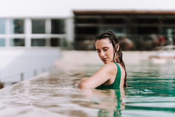 Chica joven delgada posando en piscina de hotel de vacaciones en traje de baño