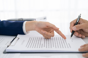 Fototapeta premium Hands of lawyer pointing at paper for businessman signing contract. Solicitor, legal advisor helping mature client to fill up document, medical insurance form, will, affixing signature. Paperwork