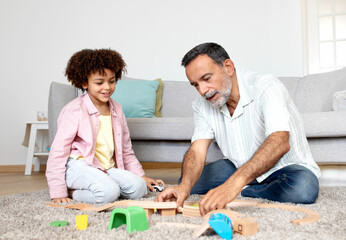 Smiling Hispanic Grandfather and Little Grandson Enjoying Toy Fun Indoors