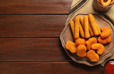 Tasty ketchup, chicken nuggets and cheese sticks on wooden table, flat lay. Space for text