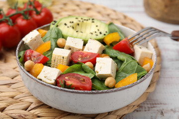 Bowl of tasty salad with tofu and vegetables on white wooden table, closeup