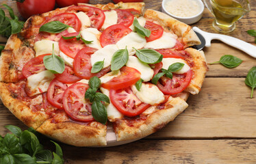 Delicious Caprese pizza with tomatoes, mozzarella and basil served on wooden table